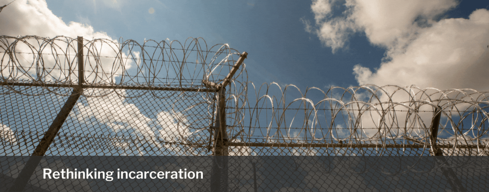 Image of a barbed wire fence with a blue skies and sunny background.