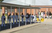 Photo of a women incarcerated walking in a single file line outdoors. 