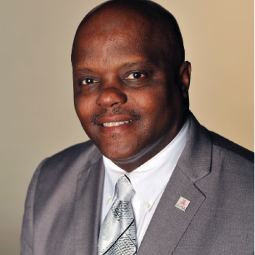 Head shot of Ronald D. Simpson-Bey. Bald with a black mustache and wearing a gray jacket.