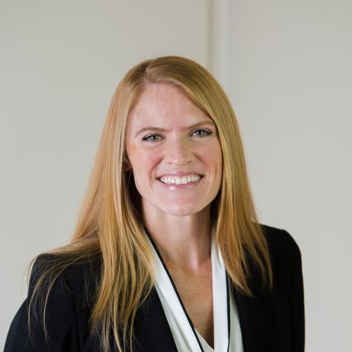 Headshot photograph of Alycia Welch. White woman with long reddish hair wearing a black blazer.