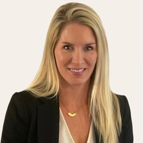 White woman with blond hair smiling at camera on beige background in a black blazer, white shirt, and gold necklace, headshot of Crystal Kimbrough